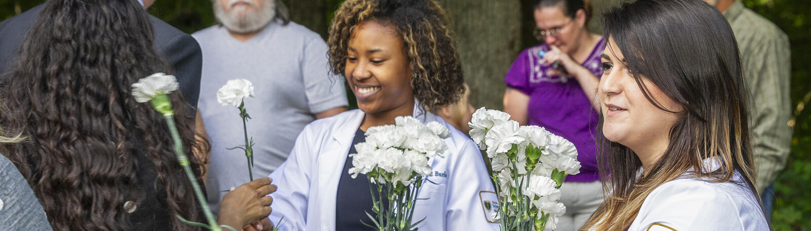 photo of medical students giving flowers to attendees of the annual ceremony of appreciation