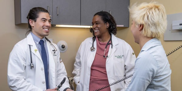 photo of a professor, student, and patient in an exam room